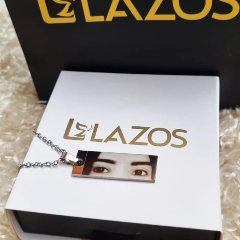 Dije rectangular plateado con fotograbado de una mirada sobre caja LAZOS