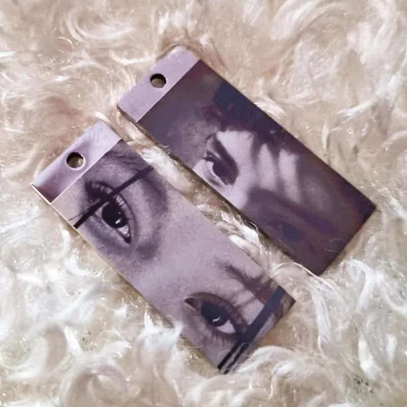 Pareja de dijes rectangulares plateados con fotograbado de rostros