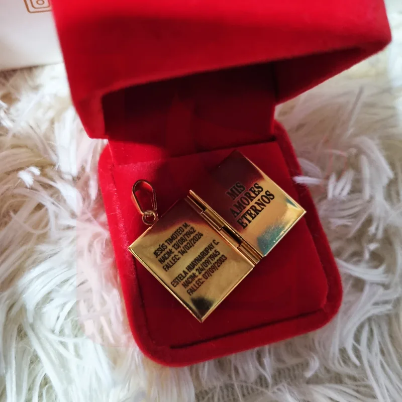 Relicario libro dorado abierto con texto conmemorativo